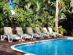 a group of lounge chairs next to a swimming pool at Alloro Jungle Villas in Puerto Viejo