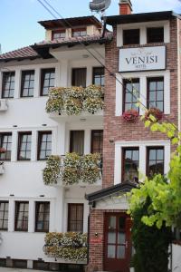 a white building with lots of windows and plants at Hotel Venisi in Prizren