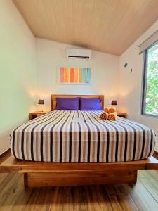 a bedroom with a large bed with a striped comforter at Alloro Jungle Villas in Puerto Viejo