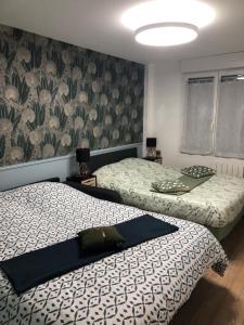 - une chambre avec 2 lits et un mur orné de fleurs dans l'établissement Appartement Chaleureux -Paris-CDG-RER B-Parc des Expos de Villepinte-Disneyland-Asterix-Stade de France-, à Vaujours