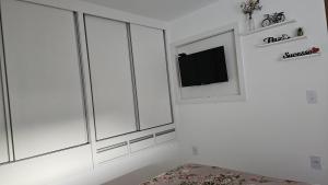 a white room with white cabinets and a tv at Cantinho na Serra - Apartamento in Santa Maria Madalena