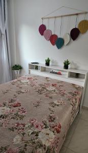 una camera da letto con un letto con un copriletto floreale e cuori sul muro di Cantinho na Serra - Apartamento a Santa Maria Madalena