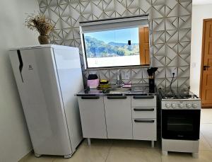 a kitchen with a refrigerator and a sink and a stove at Cantinho na Serra - Apartamento in Santa Maria Madalena