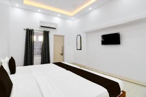 um quarto com uma cama branca e uma televisão de ecrã plano em OYO Orchid Guest House em Durgapur