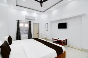 um quarto branco com uma cama e uma televisão em OYO Orchid Guest House em Durgapur