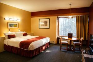 ein Hotelzimmer mit einem Bett, einem Tisch und einem Fenster in der Unterkunft The Inn at Crumpin-Fox in Bernardston