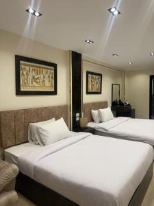 2 bedden in een hotelkamer met witte lakens bij Crowne Pyramids view inn in Caïro