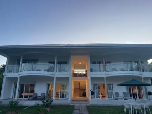 ein großes weißes Gebäude mit Stühlen und einem Sonnenschirm in der Unterkunft Tropic Villa Annex in Grand'Anse Praslin