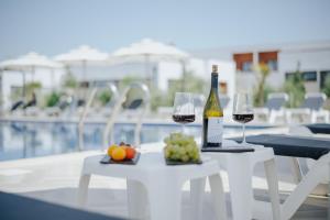 a table with two glasses of wine and fruit next to a pool at Family Bungalows in Ulcinj