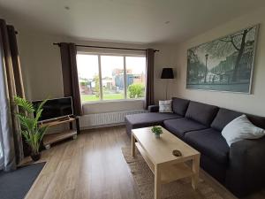 uma sala de estar com um sofá azul e uma televisão em Cozy chalet near Amsterdam at Camping Venhop em Berkhout