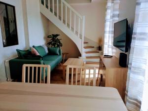 a living room with a green couch and a staircase at V.KLS Appartement 3 in Languidic