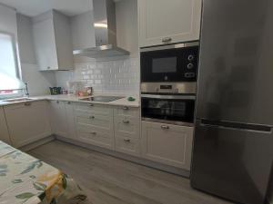 a kitchen with white cabinets and a black refrigerator at Apartamento acogedor en La Camocha-Gijón in Monte de Huerces