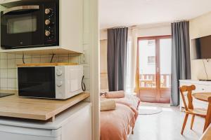 a kitchen with a microwave and a living room at Studio central Brides-les-Bains in Brides-les-Bains