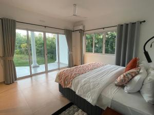 a bedroom with a bed and large windows at Tropic Villa Annex in Grand'Anse Praslin