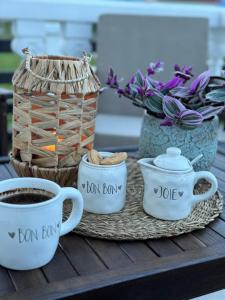 a table with two cups of coffee and a basket of flowers at White Home in Žabljak