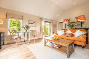 a living room with an orange couch and a table at Elegant luxurious cottage - The Dove House in Ipswich