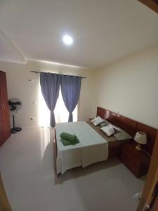 1 dormitorio con 1 cama y una ventana con cortinas moradas en Nifa House, en Espargos