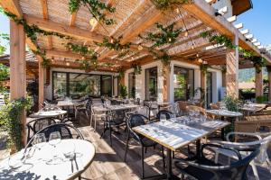 a restaurant with tables and chairs under a wooden pergola at L'Arcalod Hôtel Restaurant & Spa in Doussard
