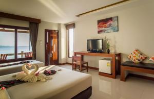 a bedroom with two beds and a television and a table at Neptune's Villa in Haad Rin