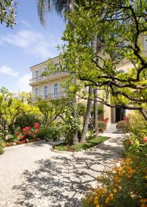 um grande edifício branco com árvores e flores em Hotel Villa Elisa & Spa em Bordighera