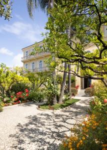 a large white building with trees and flowers at Hotel Villa Elisa & Spa in Bordighera