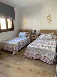 a bedroom with two beds and a window at Apartamentos rurales El Hondón del Lugar in Hoyos