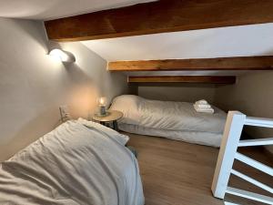 a bedroom with two beds and a table with a lamp at L'Escale aux portes des Gorges de l'Ardèche in Saint-Martin-dʼArdèche