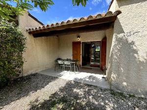 a patio with a table and chairs in front of a house at L'Escale aux portes des Gorges de l'Ardèche in Saint-Martin-dʼArdèche