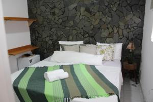 1 dormitorio con 1 cama con manta verde y gris en Pousada Hosp Cantinho de Minas, en Cabo Frío