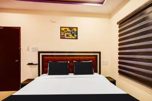 1 dormitorio con 1 cama con cabecero de madera en OYO AADYA INN, en Tirupati