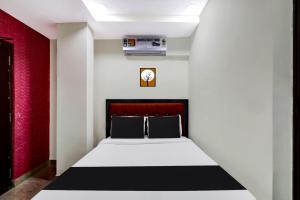 Cama en habitación con pared roja en OYO AADYA INN, en Tirupati
