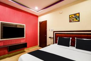 OYO AADYA INN في تيروباتي: غرفة فندقية بسرير وتلفزيون بشاشة مسطحة