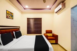 1 dormitorio con 1 cama y 1 silla en OYO AADYA INN, en Tirupati