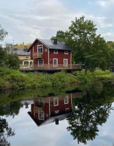 Ein rotes Haus spiegelt sich im Wasser wider in der Unterkunft Sea Side Cabin in Borlänge