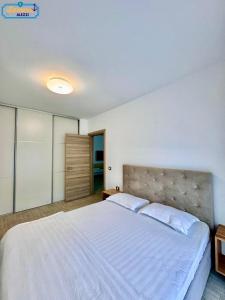 a bedroom with a large white bed with two pillows at Lamera - Alezzi Apartament langa mare cu acces la piscina, jacuzzi, sauna si sala de fitness in Năvodari +18 photos