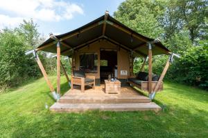 cenador con terraza de madera en un campo en Safari tent 1 op Wellness Camping en B&B Stoltenborg, en Meddoo