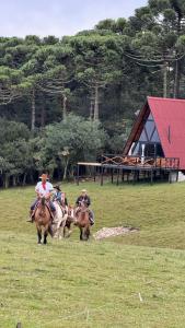 un grupo de personas montando caballos en un campo en Chalés Corucacas en Cambara do Sul