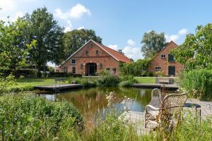 una casa con un estanque delante de ella en Safari tent 1 op Wellness Camping en B&B Stoltenborg en Meddoo