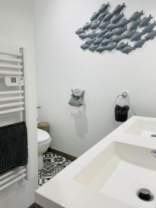 uma casa de banho branca com um lavatório e um WC em Au Petit Bonheur chez Bambina em Leynes