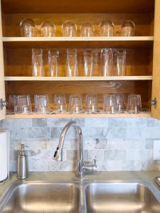 a kitchen counter with a sink and glasses on shelves at Magnolia Garden Cottage in Seattle