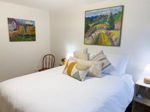 a bedroom with a white bed with two paintings on the wall at Magnolia Garden Cottage in Seattle