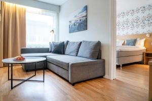 a living room with a couch and a bed at First Hotel Dragonen in Umeå
