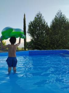 a young boy in a swimming pool holding up a green inflatable at Quinta da Telheira in Vila Real