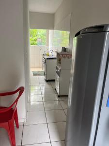 a kitchen with a red chair and a refrigerator at Hotel da Gaúcha in Aragarças