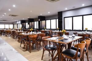 a restaurant with wooden tables and chairs and windows at Plaza Inn Small Town Flat in Sao Paulo