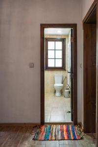 ein Bad mit WC und eine Tür mit Teppich in der Unterkunft Деребеевата къща in Cherni Vrŭkh