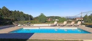 a swimming pool with chairs and a bunch ofitures at Casa da Americana II in Boqueijón