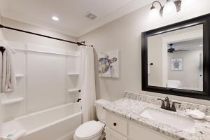 a bathroom with a sink and a toilet and a mirror at Beach Cottage in Dauphin Island +43 photos