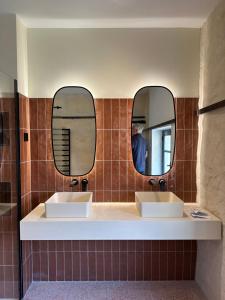 a bathroom with two sinks and two mirrors at L'Arlésienne in Arles