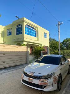 une voiture blanche garée devant une maison dans l'établissement Tiny Apartment By Merengue House, à Saint-Domingue